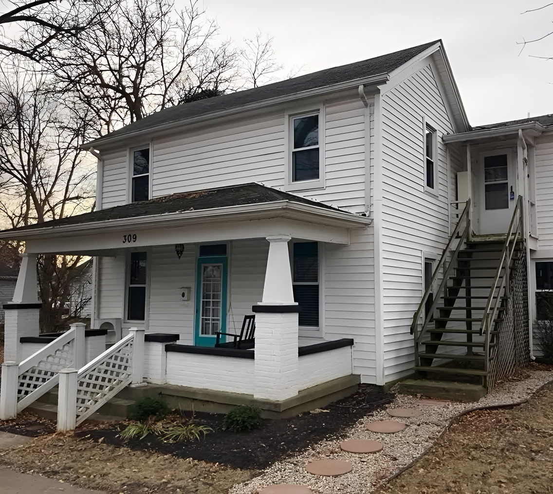 White two-story house with exterior staircase.