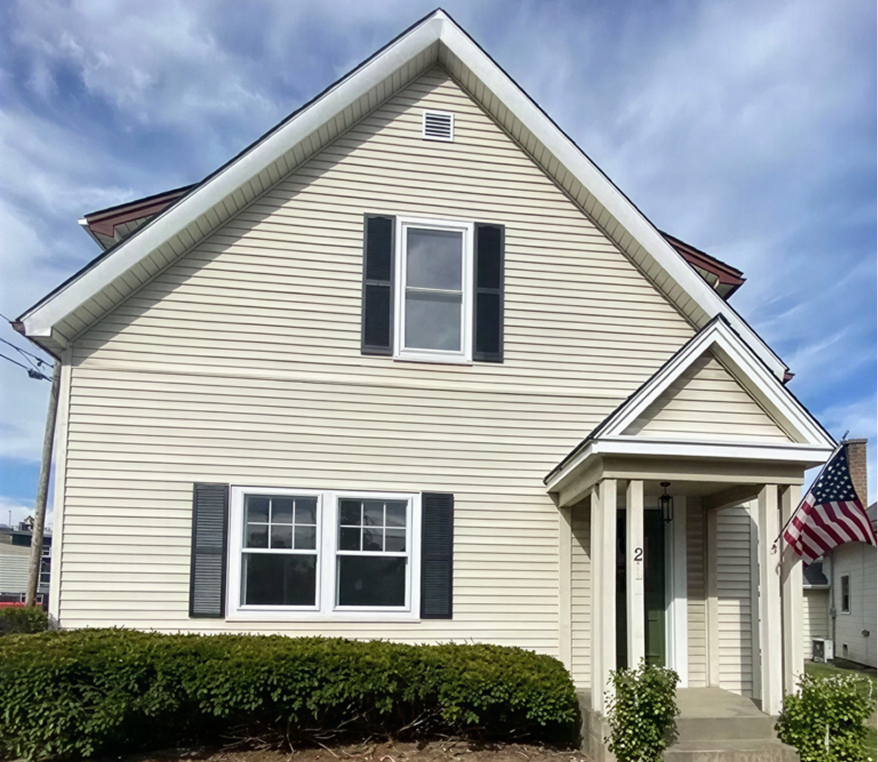 House with American flag and cloudy sky.