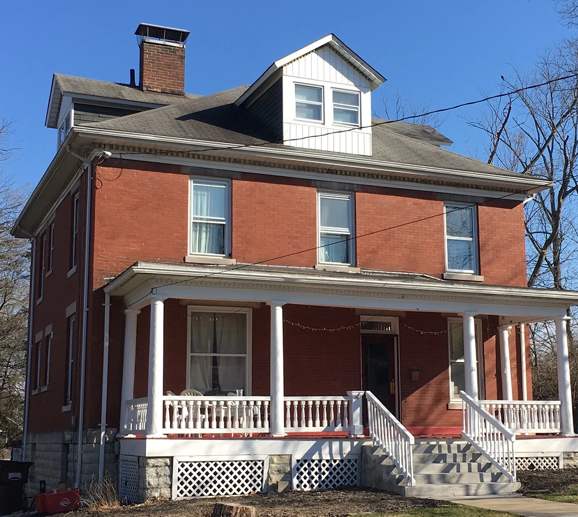 Brick house with porch and dormer windows.
