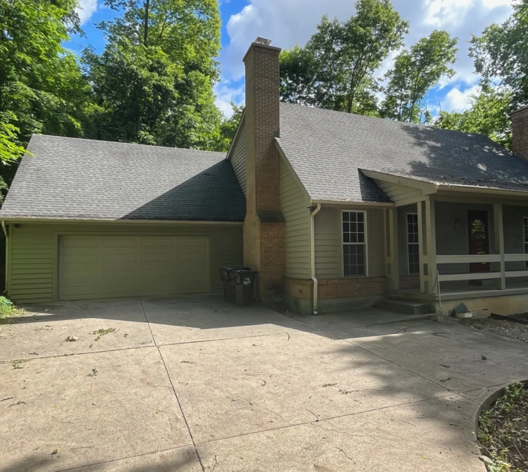 House with driveway and surrounding trees.