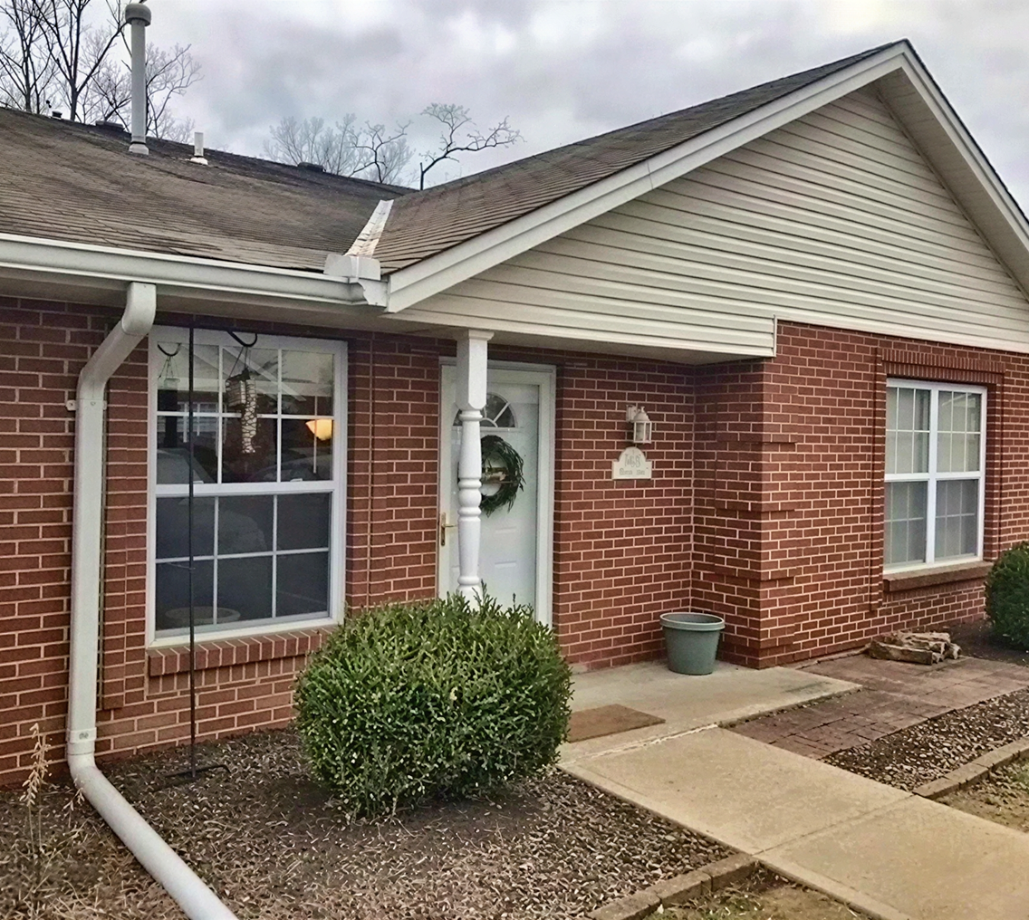 Brick house exterior with green shrubbery.