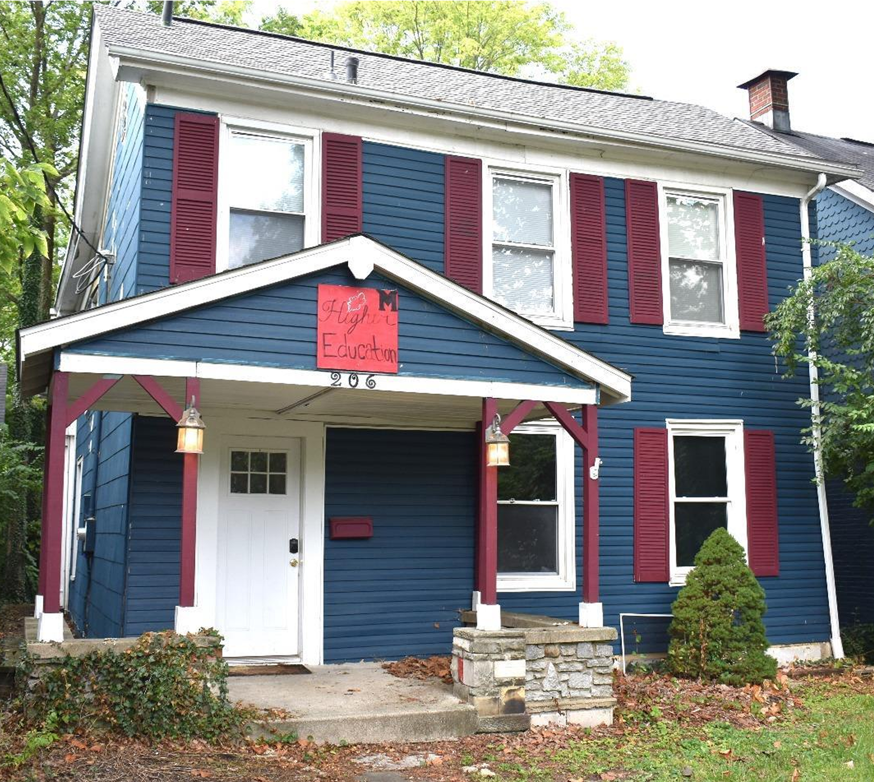 Blue house with red shutters and sign.
