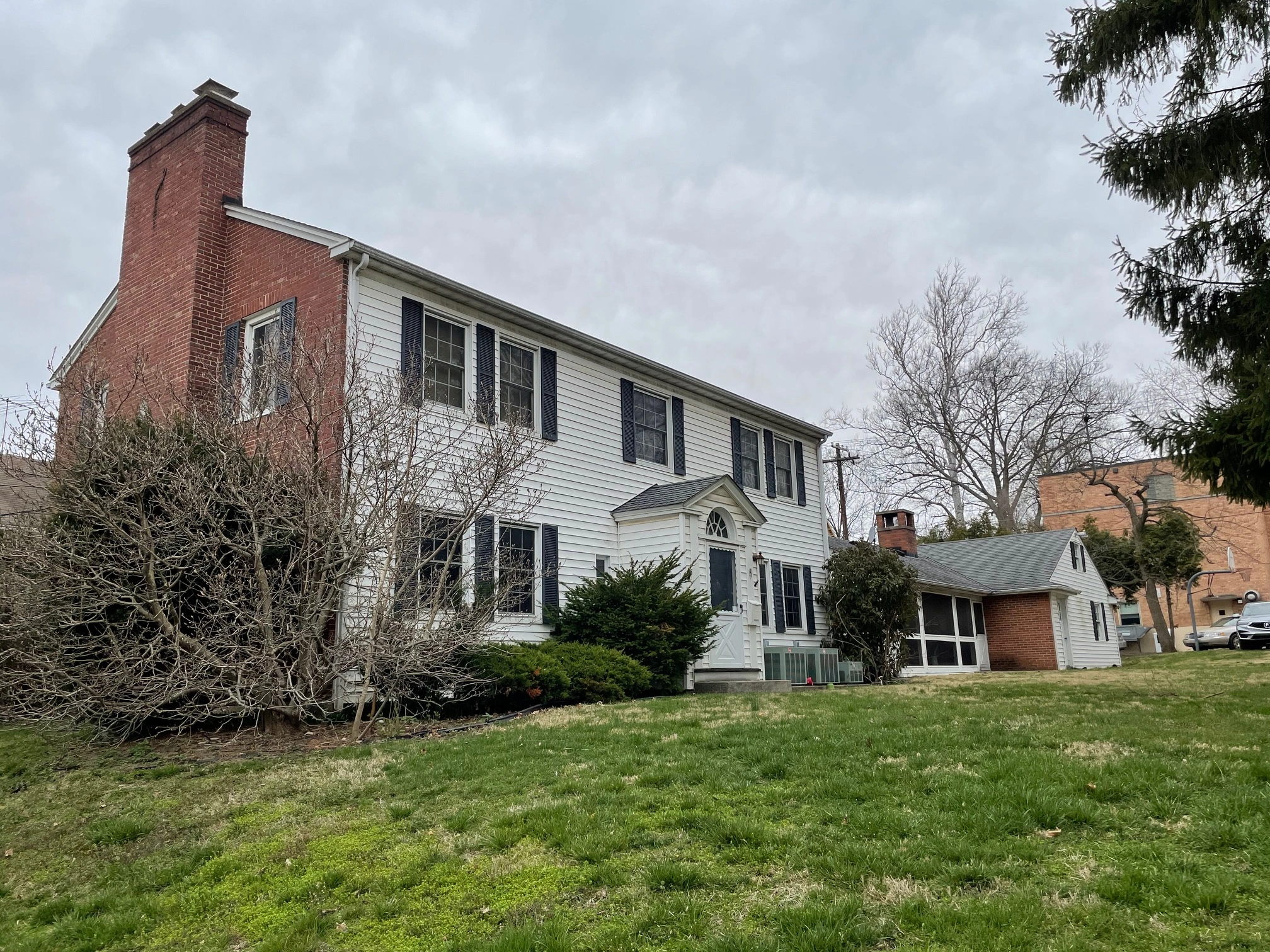 Colonial-style house with dark shutters and bare trees